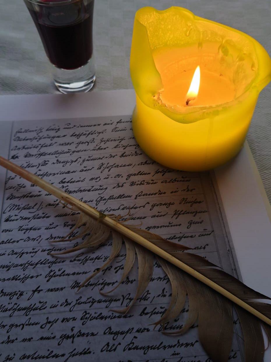 Bild mit Weinglas, Kerze, Blatt Papier und einem Federkiel